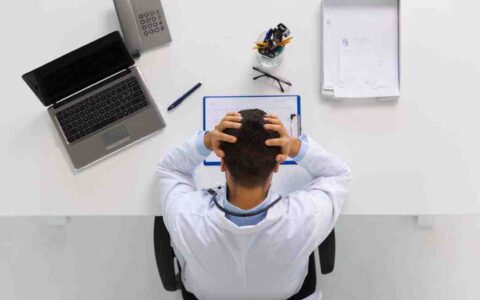 Person holding his head in his hands looking at paper on desk