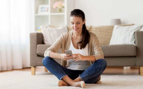 Person sitting in lounge looking at her phone and smiling