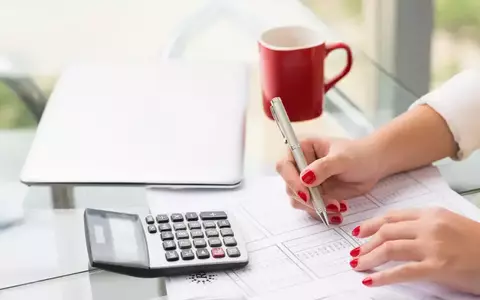 Individual at desk with calculator doing calculations