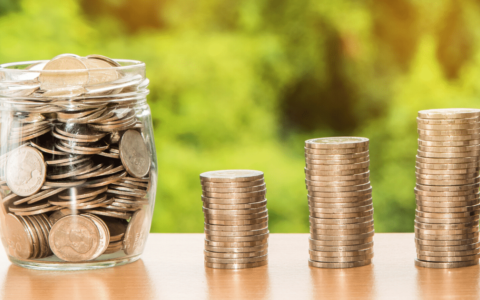 Coins stacked in three rows next to coins in a jar