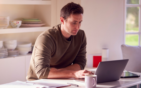 Individual in kitchen with laptop