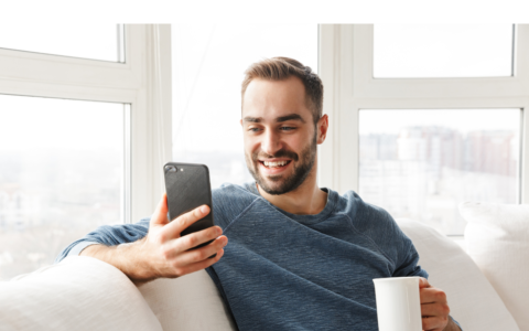 Person looking happily at phone holding coffee