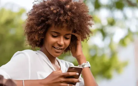 Person outside looking at phone with content and happy smile