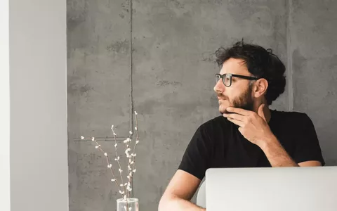 Person in front of laptop computer looking to the side considering