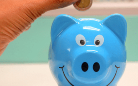 Hand putting coin in blue piggybank