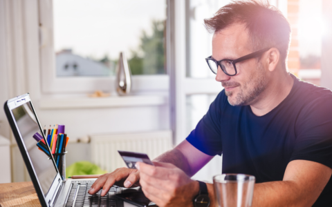 Person wearing glasses staring at phone and computer happily