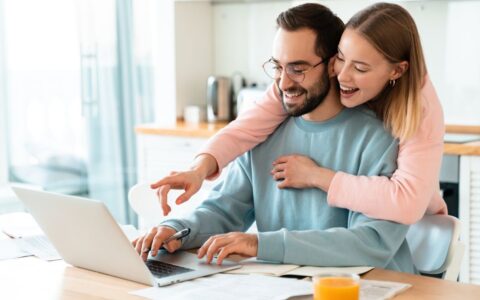 Happy couple laughing and looking at their computer
