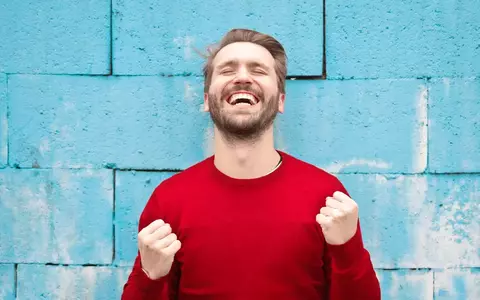 Happy Person celebrating against blue wall