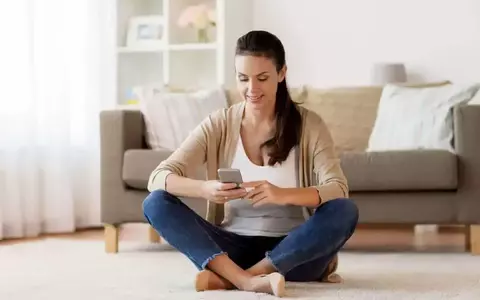 Happy Person Sitting On Floor And Texting Message On Smartphone