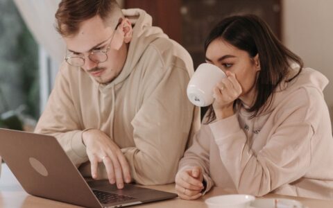 Couple looking at laptop drinking coffee together