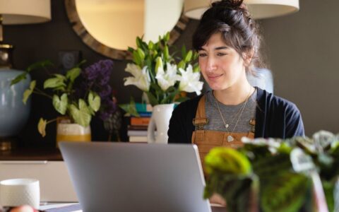 Person working on her laptop at home with plants and mirror in the background