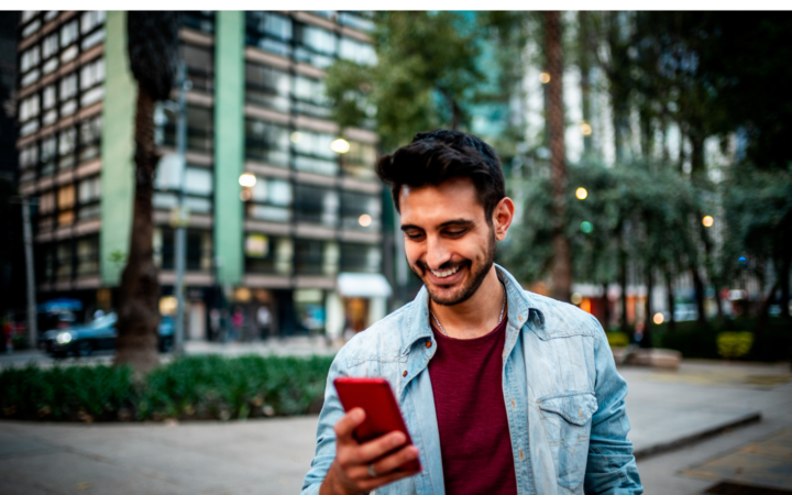 Person in the city smiling down at his phone