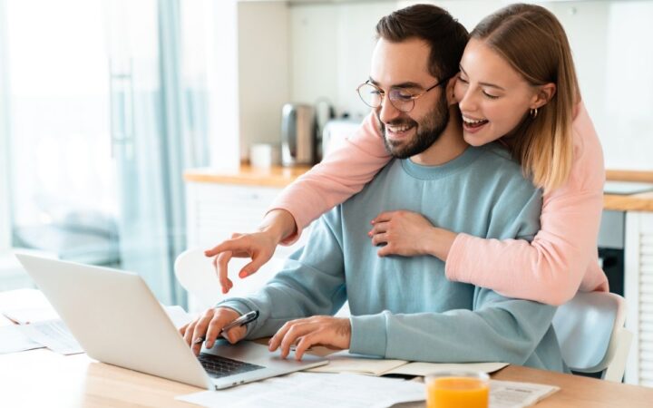 Happy couple laughing and looking at their computer